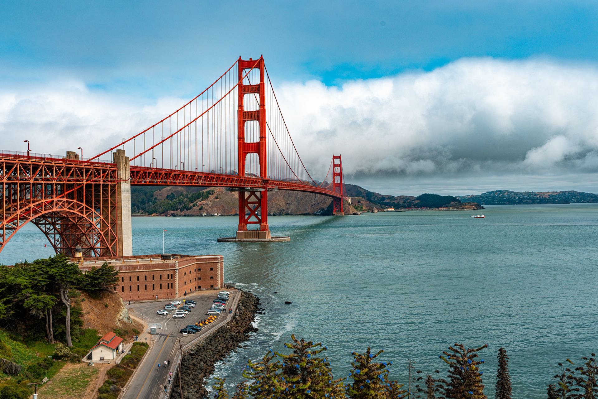 Elevated photograph of the Golden Gate Bridge spanning the bay under a sky heavy with clouds